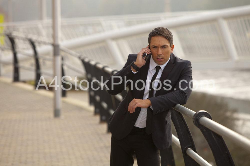 A muscular looking man in a suit talking earnestly on his mobile. Could be taking instructions, could be security, checking emails etc.