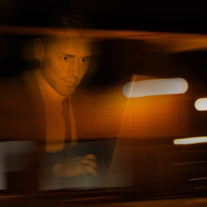 A businessman in a suit at a computer in a darkened room or suspicious environment