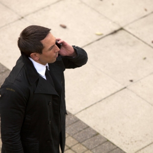 A security guard on the mobile while checking something out, possibly a building