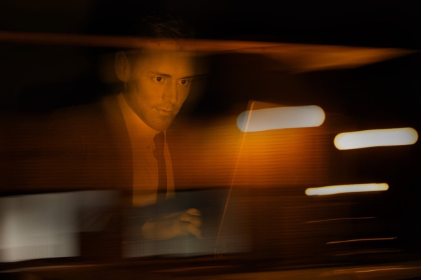 A businessman in a suit at a computer in a darkened room or suspicious environment