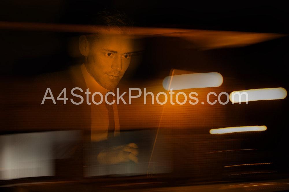 A businessman in a suit at a computer in a darkened room or suspicious environment