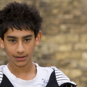 A young mixed race boy standing in front of a wall in an urban setting