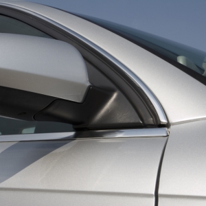 A close up image of a silver car against a clear blue sky