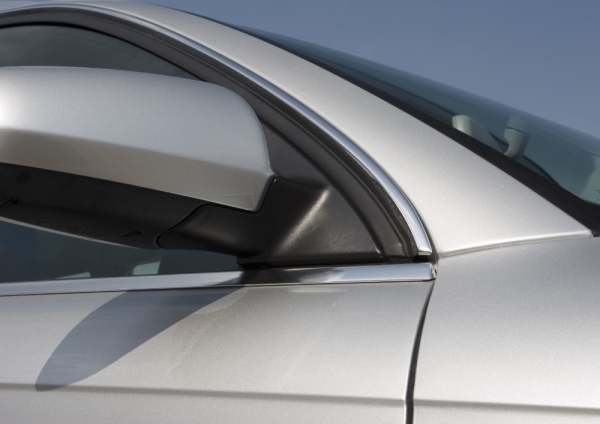 A close up image of a silver car against a clear blue sky