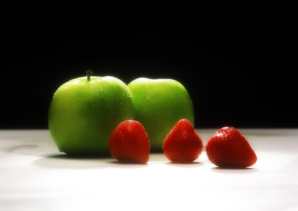 Apples and strawberries against a black background