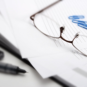 Macro view of business invoice with paperwork, books, pen and glasses