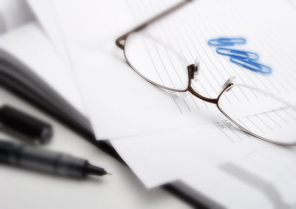 Macro view of business invoice with paperwork, books, pen and glasses