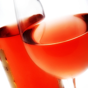 A close up macro view of a bottle of rose wine with a glass of rose