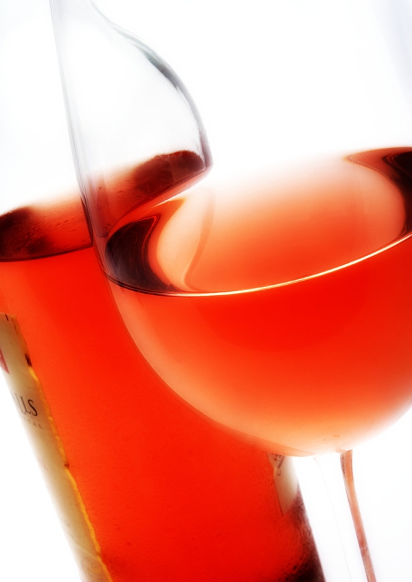 A close up macro view of a bottle of rose wine with a glass of rose