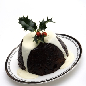 A Christmas pudding with cream and a sprig of holly on top