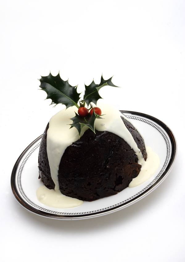 A Christmas pudding with cream and a sprig of holly on top