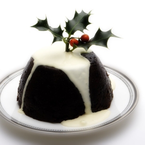 A Christmas pudding with cream and a sprig of holly on top