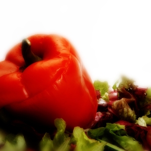 A stuffed red pepper with a green salad on a white plate