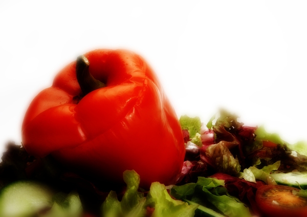 A stuffed red pepper with a green salad on a white plate