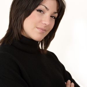 Pretty brunette girl with arms folded smiling at camera