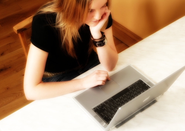 A girl working on a laptop computer seen from above