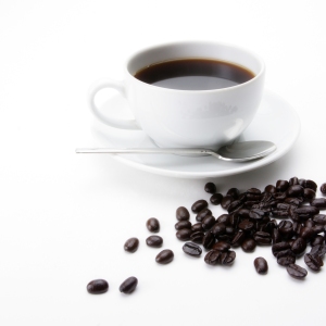 A cup of coffee with some arabica coffee beans