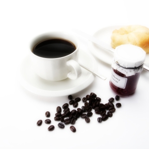 A cup of coffee with some arabica coffee beans, a doughnut & jam