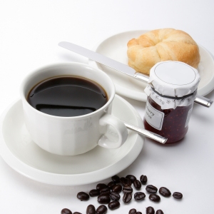 A cup of coffee with some arabica coffee beans, jam and doughnut