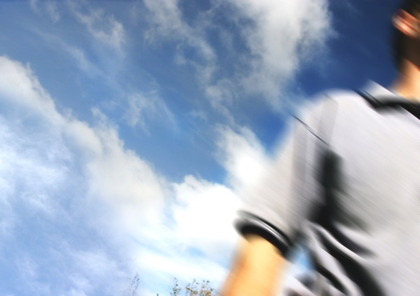 Blurred image of man walking out of shot with blue summer sky in the background