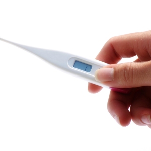 A modern digital thermometer held in a hand