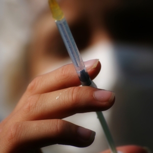 Close up view of a syringe held by out of focus nurse