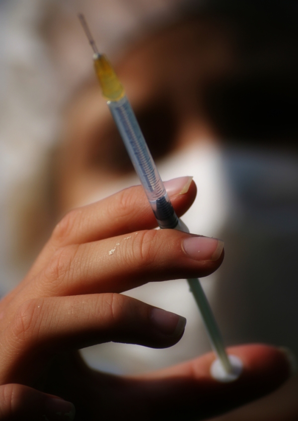 Close up view of a syringe held by out of focus nurse