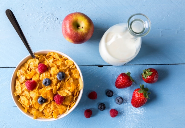 Cornflakes in a bowl with milk and fruits.