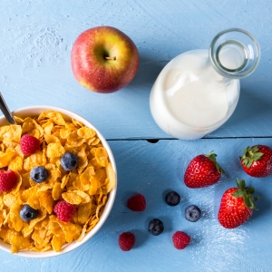 Cornflakes in a bowl with milk and fruits.