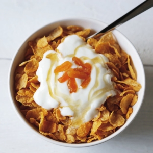 Cornflakes in a bowl with yogurt and honey.