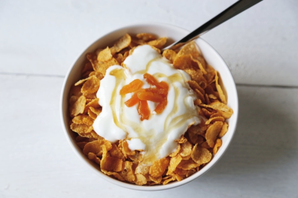 Cornflakes in a bowl with yogurt and honey.