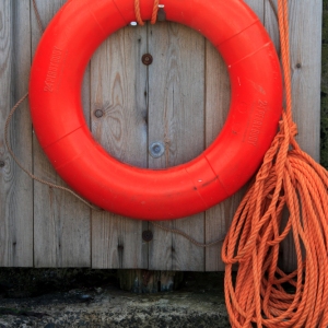 Red lifebelt on a wooden background designed to be thrown to a person in the water.