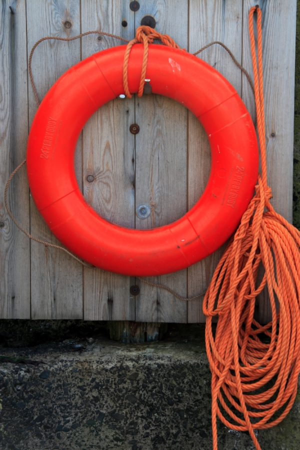 Red lifebelt on a wooden background designed to be thrown to a person in the water.