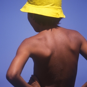 Young boy in yellow hat fishing from the rocks by the seaside