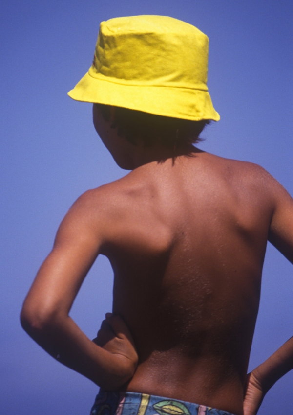 Young boy in yellow hat fishing from the rocks by the seaside