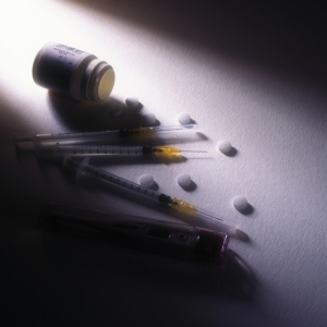 A moody photo of some syringes and pills