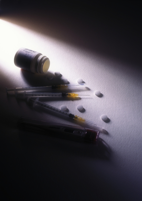 A moody photo of some syringes and pills