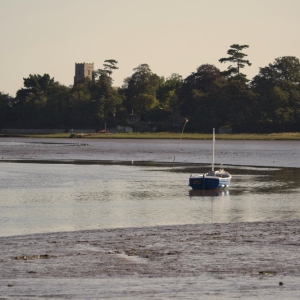 A small sailing boat moored in the estuary at low tide on the River Alde near Snape Maltings