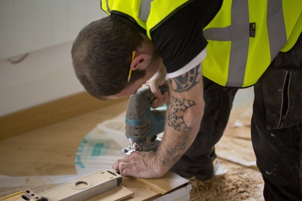 A building site carpenter cutting skirting board