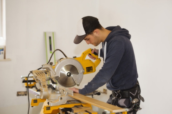 A building site carpenter cutting mitres on a table saw