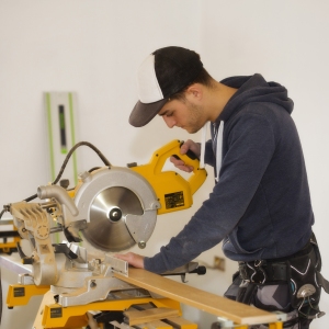 A building site carpenter cutting mitres on a table saw