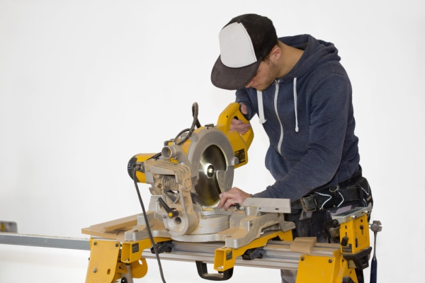 A building site carpenter cutting mitres on a table saw, isolated