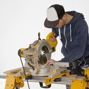 A building site carpenter cutting mitres on a table saw, isolated