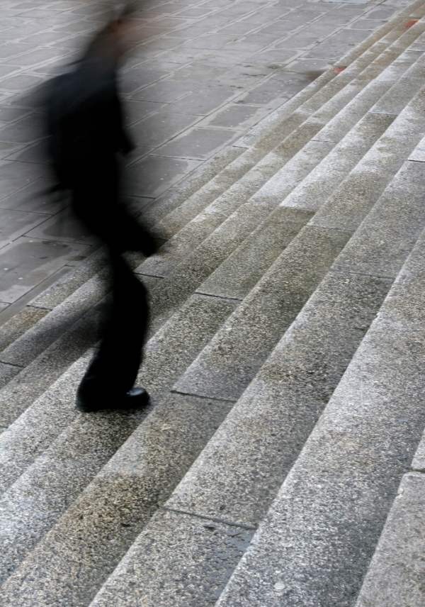 A blurred man walking up steps in the city