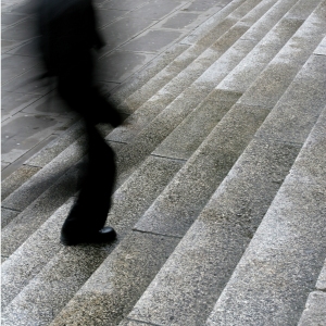 A blurred man walking up steps in the city