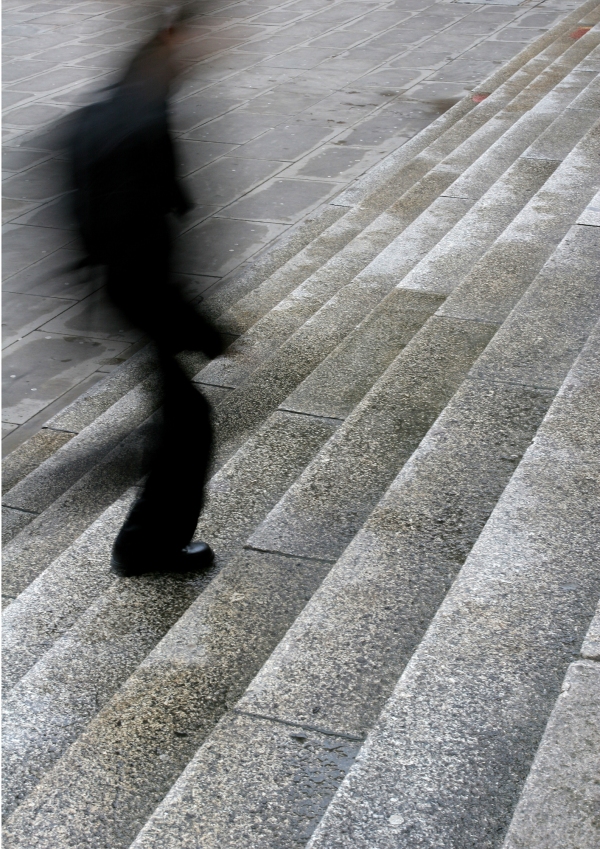 A blurred man walking up steps in the city