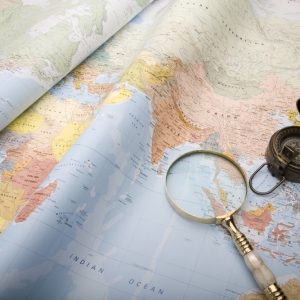 A world map with old world war ll compass and magnifying glass