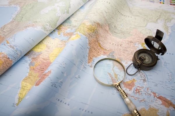 A world map with old world war ll compass and magnifying glass