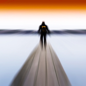 Blurred image of a man walking on a wooden jetty on a lake or sea