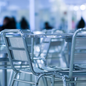 A sesaturated image of cool cafe chairs and tables with people in the background